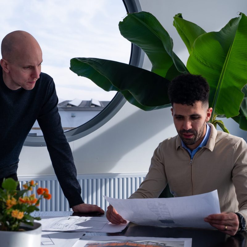 Projektmöte om byggnation av lagerhall – planering med ritningar och upphandling.
