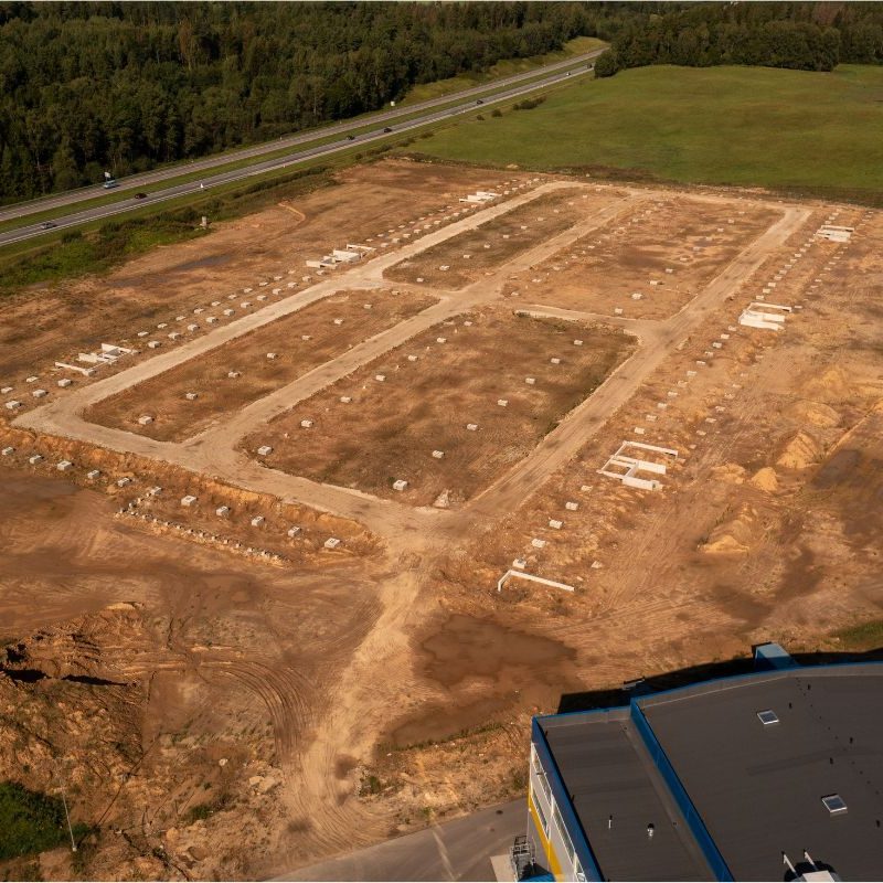 Flygbild över markarbete för industrihall i tidigt skede med schakt, höjdsättning och grundförberedelser.