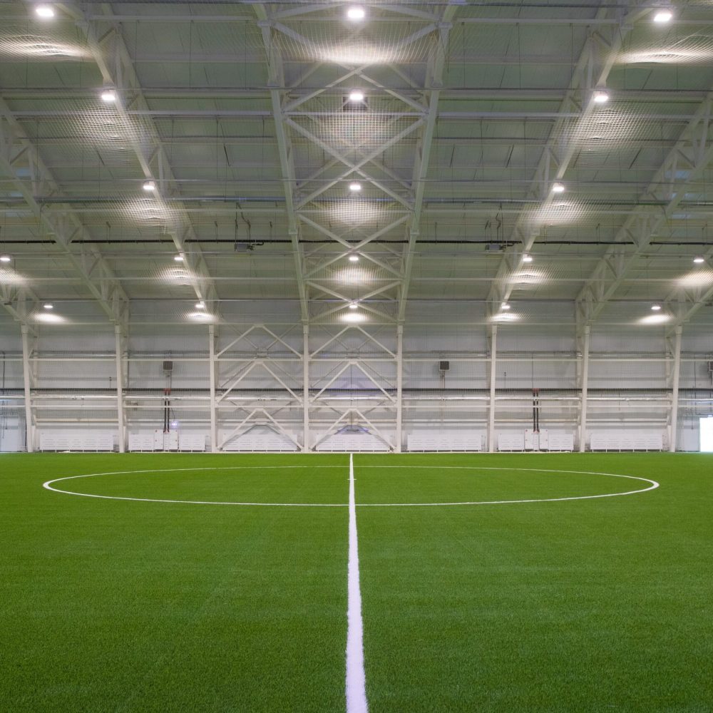 Interiör av sporthall med konstgräs – Hallkonsulten Interiör av modern sporthall med konstgräs och stålkonstruktion – Hallkonsulten