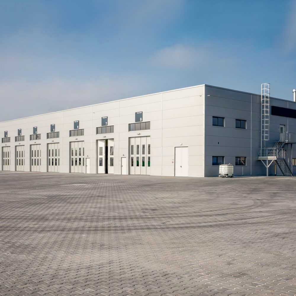 Verkstadshall – modern industribyggnad Modern verkstadshall i stål med portar och ljus fasad – exempel på nyproducerad industribyggnad.